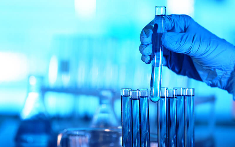 test tubes and other lab equipment and a gloved hand holding a test tube